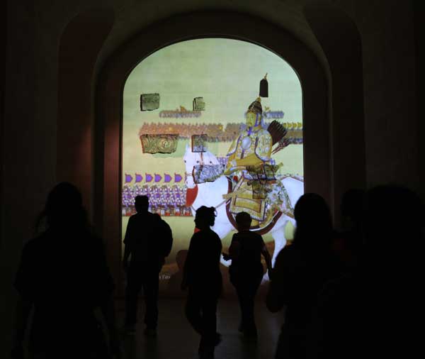 Visitors walk past a projective of the portrait of Emperor Qianlong in the Louvre Museum in Paris, capital of France, on Sept. 26, 2011. About 130 artifacts from the Forbidden City, China's ancient imperial palace museum, started to greet the French public in the Louvre Museum on Monday in an exhibition that will run until Jan. 9, 2012.