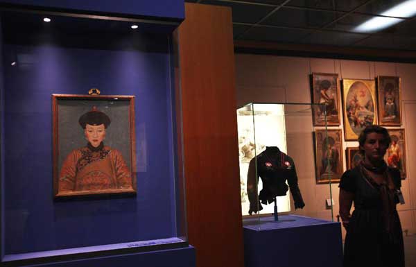 A woman stands beside a Chinese antique in the Louvre Museum in Paris, capital of France, on Sept. 26, 2011. About 130 artifacts from the Forbidden City, China's ancient imperial palace museum, started to greet the French public in the Louvre Museum on Monday in an exhibition that will run until Jan. 9, 2012.