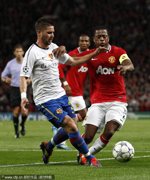 Manchester United's Patrice Evra (right) vies for the ball against FC Basel's Markus Steinhofer (left) during their Champions League Group C soccer match at Old Trafford on Tuesday, Sept. 27, 2011.