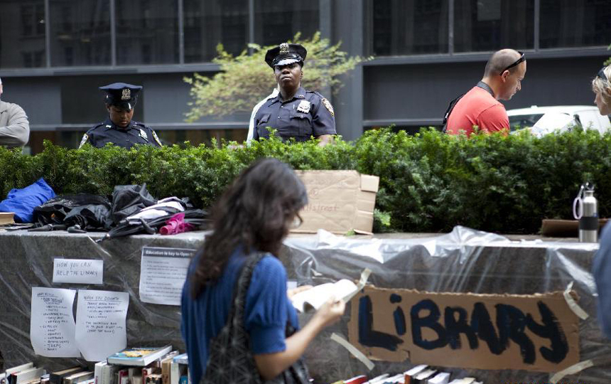 Police watch over protesters at a park near the Wall Street in New York, the United States, on Sept. 27, 2011. After several streets around the Wall Street have been blockaded since Sept. 16, protesters pitched their tents at the Bowling Green and Battery Park to continue their demonstration.