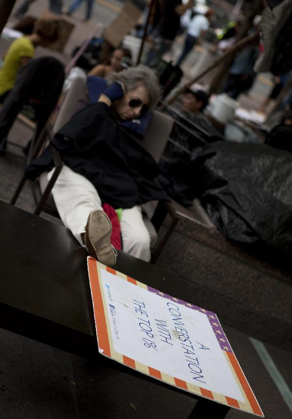 A protester rests on a chair in a park near the Wall Street in New York, the United States, on Sept. 27, 2011. After several streets around the Wall Street have been blockaded since Sept. 16, protesters pitched their tents at the Bowling Green and Battery Park to continue the demonstration.