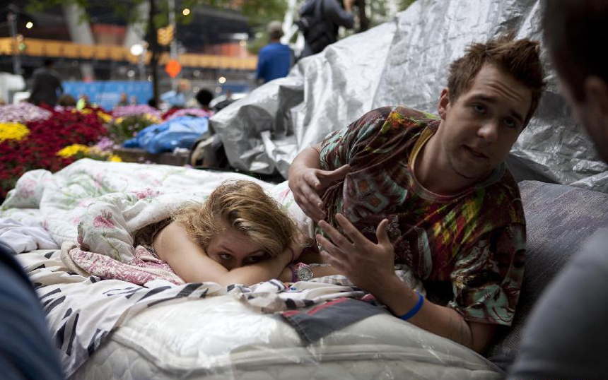 Protestors talk with photojournalists in a park near the Wall Street in New York, the United States, on Sept. 27, 2011. After several streets around the Wall Street have been blockaded since Sept. 16, protesters pitched their tents at the Bowling Green and Battery Park to continue the demonstration.