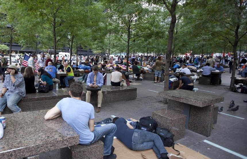 Protesters sit at a plaza near the Wall Street in New York, the United States, on Sept. 27, 2011. After several streets around the Wall Street have been blockaded since Sept. 16, protesters pitched their tents at the Bowling Green and Battery Park to continue their demonstration. 