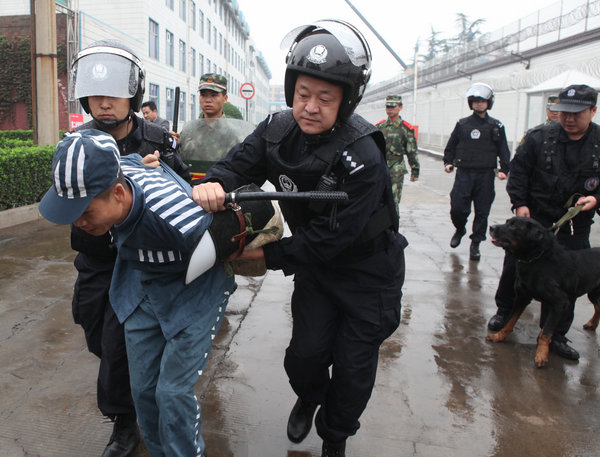 Prison guards and armed police officers apprehend a 'prisoner' who escaped from prison during a drill at Yuxi prison in Luoyang, Central China's Henan province on Sept 27, 2011. More than 100 prison guards and armed police officers participated in the anti-terror drill. The drill was held to boost prison safety. [Photo/CFP]