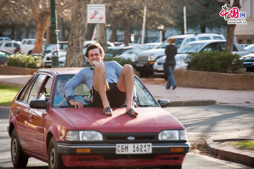 One student sit on the hood of a fast moving Ford, seemingly on a bet, chuckles for the unexpected encounter with the photojournalist. [Maverick Chen / China.org.cn]