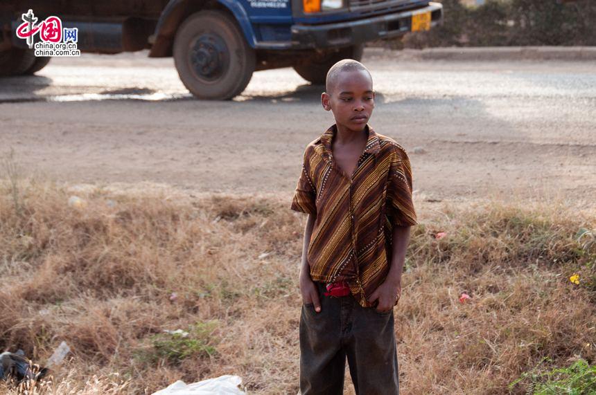 One boy stands at the road side doing nothing but watching the traffic jam in Arusha region of Tanzania. [Maverick Chen / China.org.cn]