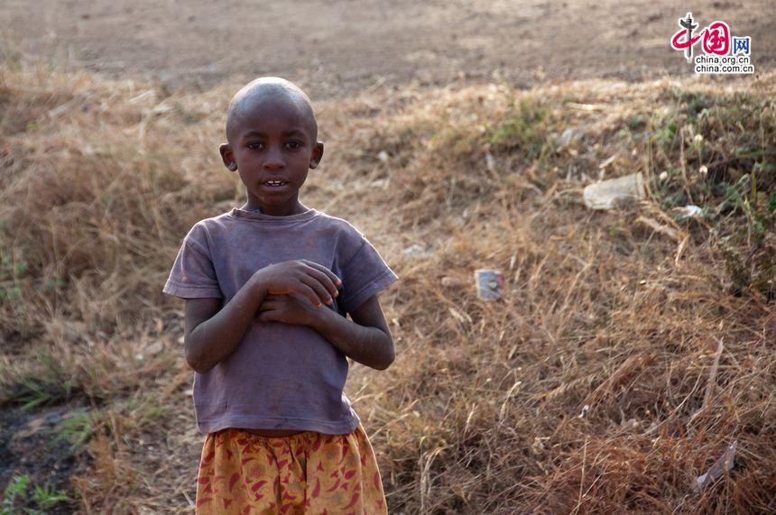 The boy, who is also watching the stuck-up vehicles in a traffic jam in rural Tanzania, waves to the photographer, perhaps to show his hospitality to us &apos;foreigners&apos;. [Maverick Chen / China.org.cn]