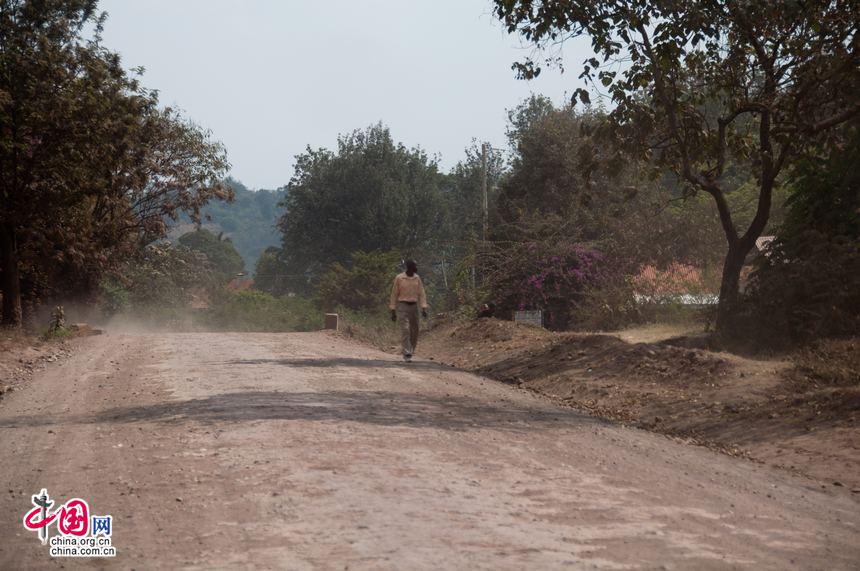 One man dressed in relatively decent clothes walks on a dusty village road in Arusha region, north of Tanzania. [Maverick Chen / China.org.cn]