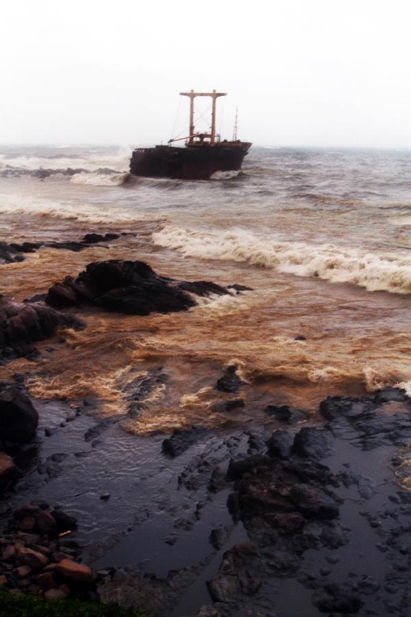 Photo taken on Oct. 3, 2011 shows the cracked cargo ship and the rocks polluted by the leaked oil, at the coast near Keelung, southeast China's Taiwan. 