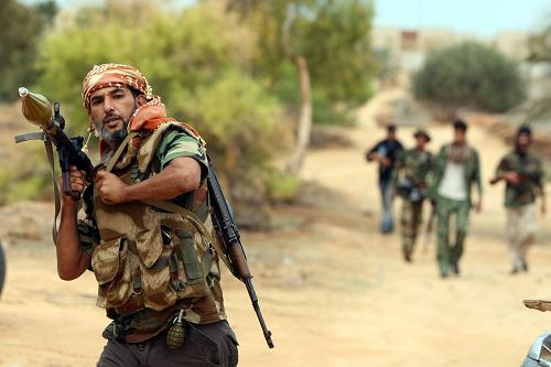 A Libyan fighter carrying an RPG walks with comrades as they advance toward the city of Sirte from the eastern side on October 6, 2011 during intense fighting that raged after forces loyal to Moamer Kadhafi tried to break a siege of the ousted strongman's hometown by fighters loyal to Libya's new regime. [Xinhua/AFP]