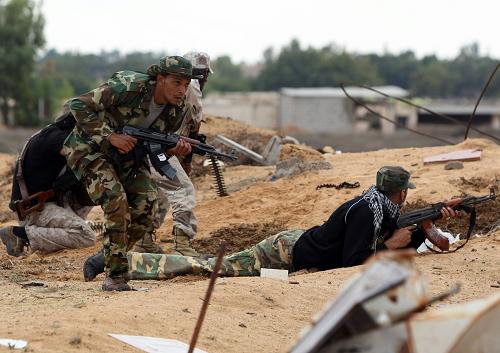 Libyan fighters seek cover as they try to advance toward the city of Sirte from the eastern side on October 6, 2011 during intense fighting that raged after forces loyal to Moamer Kadhafi tried to break a siege of the ousted strongman's hometown by fighters loyal to Libya's new regime. [Xinhua/AFP]