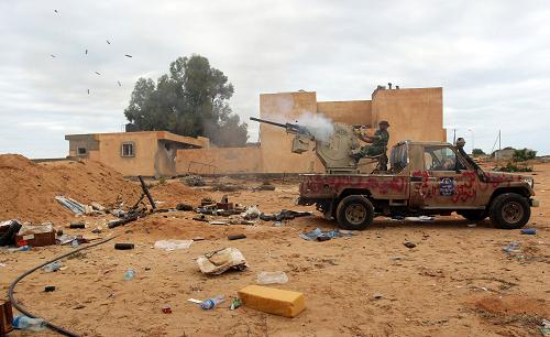 A Libyan fighter fires his machine-gun toward the frontline on the eastern outskirts of Sirte on October 6, 2011 during intense fighting that raged after forces loyal to Moamer Kadhafi tried to break a siege of the ousted strongman's hometown by fighters loyal to Libya's new regime. [Xinhua/AFP]