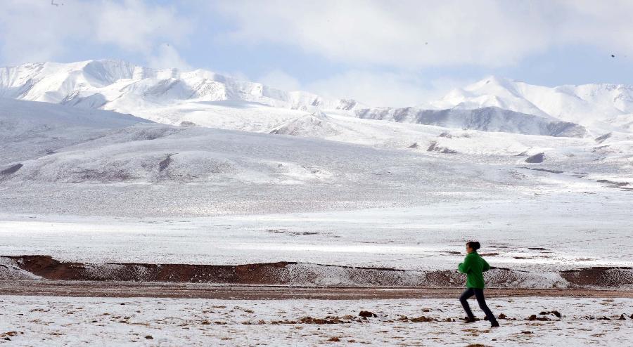 A tourist runs at the foot of the snow-capped Qilian Mountain in Qilian County, northwest China's Qinghai Province, Oct. 4, 2011. [Xinhua/Hou Deqiang]