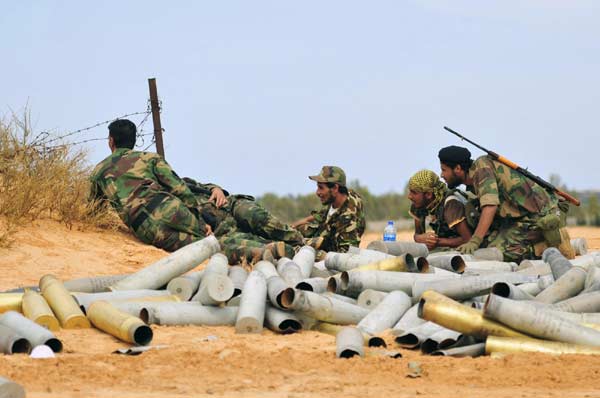 Anti-Gadhafi fighters take cover as they prepare for fighting with pro-Gadhafi forces in Sirte October 7, 2011. [Agencies]