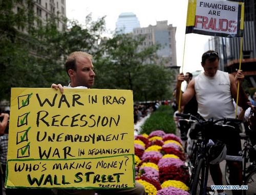 A man holds a placard during a protest at Zuccotti Park near the Wall Street in New York, the United States, on Sept. 30, 2011. Protesters have camped out near Wall Street as the Occupy Wall Street campaign entered the fourteenth day on Friday. [Shen Hong/Xinhua]