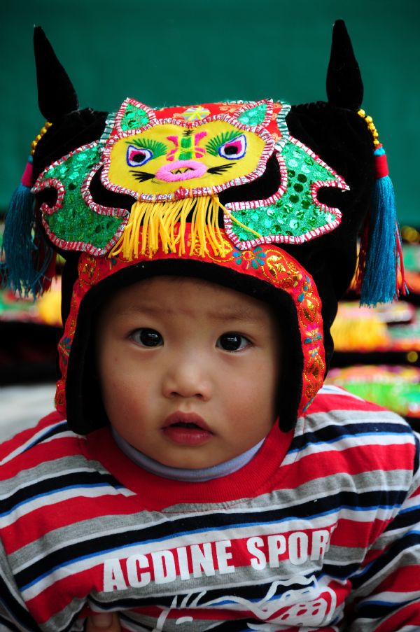 A child wears a tiger hat in Tancheng County of Linyi City in east China's Shandong Province, Oct. 5, 2011. 