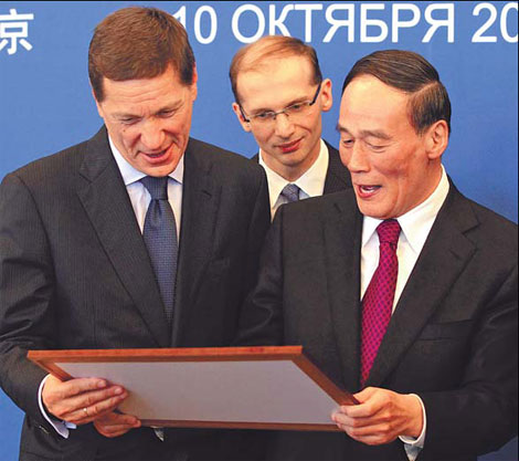 Chinese Vice-Premier Wang Qishan and his Russian counterpart Alexander Zhukov looking at a photo during the sixth China-Russia Economic and Business Summit in Beijing on Monday. In 2010, bilateral trade grew 43.1 percent year-on-year to $55.45 billion. [China Daily]