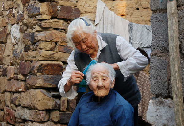 Tao combs the hair of her mother-in-law in front of their house in Zhu village, Chaohu city in East China's Anhui province, Oct 9, 2011. [Photo/CFP]
