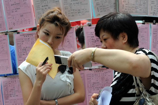 A mother (right) shows her unmarried son's photo to a potential daughter-in-law at a matchmaking fair held in Harbin, capital of Northeast China's Heilongjiang province, on Qixi, the Chinese Lovers Day, on Aug 6, 2011. [Photo/Xinhua]