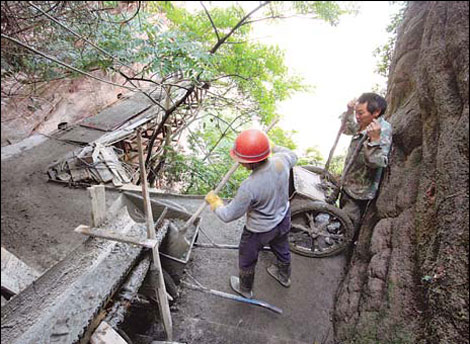 Workers make sure that the concrete flows onto the site from a mixer. [Photo by Fu Zhiyong/China Daily]