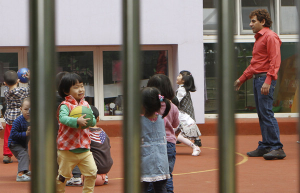 A foreign teacher and his pupils at a bilingual kindergarten in Beijing's Soho community. [Photo/China Daily]