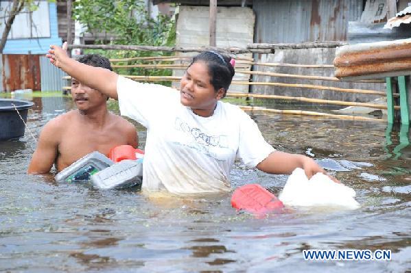 Local residents wade through floodwaters in Patumthani, Thailand, on Oct. 12, 2011. Research Center of Thai Military Bank (TMB) predicted that if the current flooding carried on until the end of this year, inflation could rise by 5.1 percent while prices of fresh foods by 11.9 percent, local media reported on Wednesday. [Rachen Sageamsak/Xinhua] 