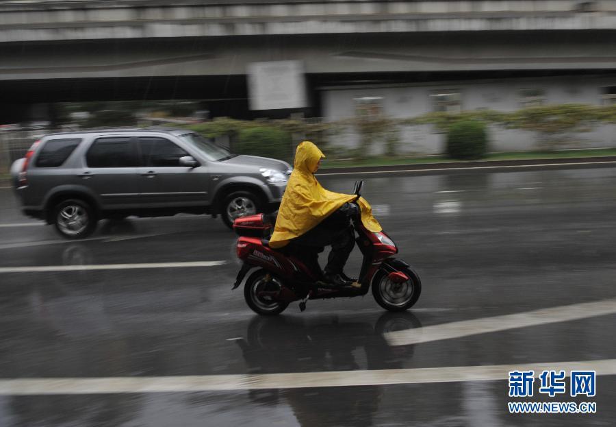 A citizen rides a battery-powered bicycle in the rain in Beijing, Oct. 13, 2011. Temparature dropped as Beijing embraced a rainfall on Thursday.