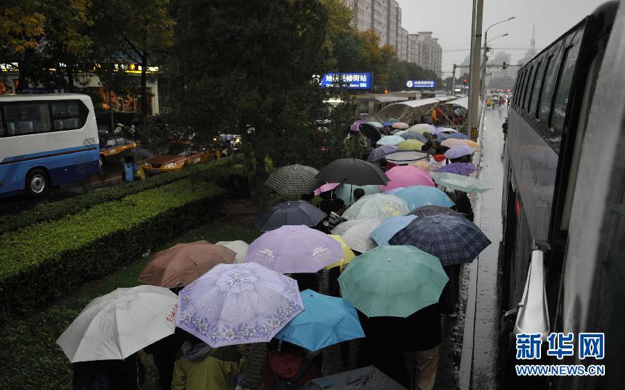 People walk in the rain to Changchunjie Station of Line 2 in Beijing, Oct. 13, 2011. Temperature dropped as Beijing embraced a rainfall on Thursday.