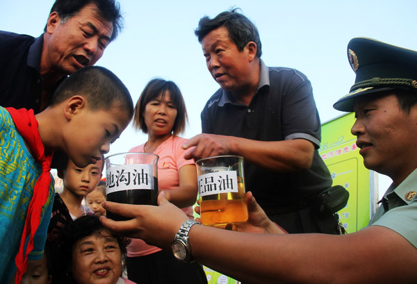 Officers with the border defense detachment in Nantong, East China's Jiangsu province, show local residents on Sept 28 how to identify gutter oil. 
