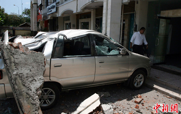 A minivan is crushed by a chunk of concrete fallen from a building after an earthquake shook Indonesia's resort island of Bali October 13. 