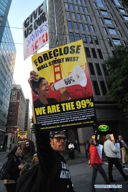 A protestor flashes a slogan board during a demonstration in San Francisco, the U.S., on Oct. 12, 2011. Hundreds of protestors attended the demonstration here on Wednesday to respond the Occupy Wall Street protest and to protest against the high umemployment rate and the wide gap between the rich and the poor. [Liu Yilin/Xinhua]