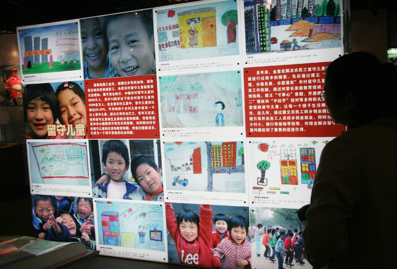 An audience watches display board about left-behind children. [CnDG by Jiao Meng]