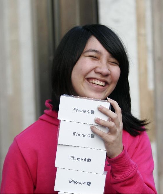 An Apple fan poses with all the iPhone 4S mobile phones she bought at the Apple Store on Regents Street in central London, Britain, Oct. 14, 2011. Apple's new mobile phone iPhone 4S went on sale in US, UK, Australia, Canada, France, Germany and Japan on Oct. 14.