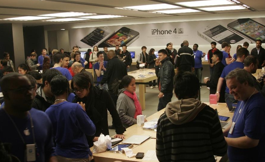 Apple fans gather at the Apple Store with iPhone 4S posters as the backdrop in central London, Britain, Oct. 14, 2011. Apple's new mobile phone iPhone 4S went on sale in US, UK, Australia, Canada, France, Germany and Japan on Oct. 14.