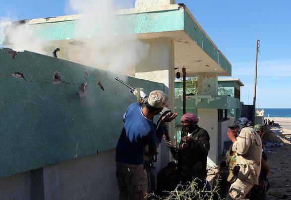 Libyan National Transitional Council (NTC) fighters fire at supporters of fallen leader Muammar Gaddafi during street battles in the city of Sirte on October 15, 2011. Fighters of the Libyan ruling National Transitional Council (NTC) on Saturday slowed down their attacks in the northern coastal town of Sirte, while their counterparts in Bani Walid managed to take control of new areas in the northwestern oasis city. [Xinhua]