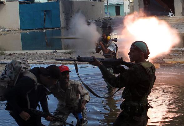 Libyan National Transitional Council (NTC) fighters fire at supporters of fallen leader Muammar Gaddafi during street battles in the city of Sirte on October 15, 2011. [Xinhua] 