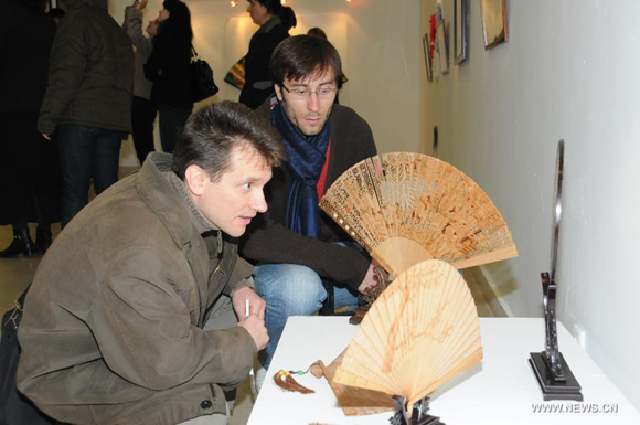 Visitors look at the fans displayed in an exhibition in the Romanian Peasant Museum in Bucharest, capital of Romania, October 17, 2011. The exhibition 'Art and craftsmanship in China - Umbrellas, Fans and Embroideries' opened on Monday and will show until Nov. 13.