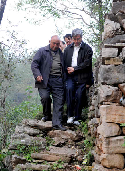 Li Congjun (right), president of Xinhua News Agency, accompanies village chief Zhang Fugen during a visit to Baiquan village in Linzhou, Henan province. Li was there on Sept 21 as a reporter to write about the residents' lives. [Provided to China Daily]