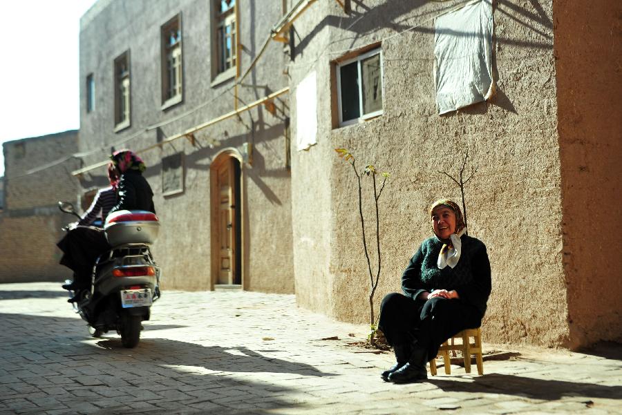 Bilekez Wbelkesem (R) enjoys the sunshine in an alley of the old city zone in Kashgar, northwest China's Xinjiang Uygur Autonomous Region, Oct. 21, 2011.