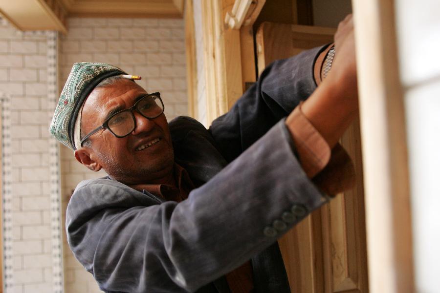 Abudulkader Roz tightens a screw of the door for a family in the old city zone of Kashgar, northwest China's Xinjiang Uygur Autonomous Region, Oct. 21, 2011.