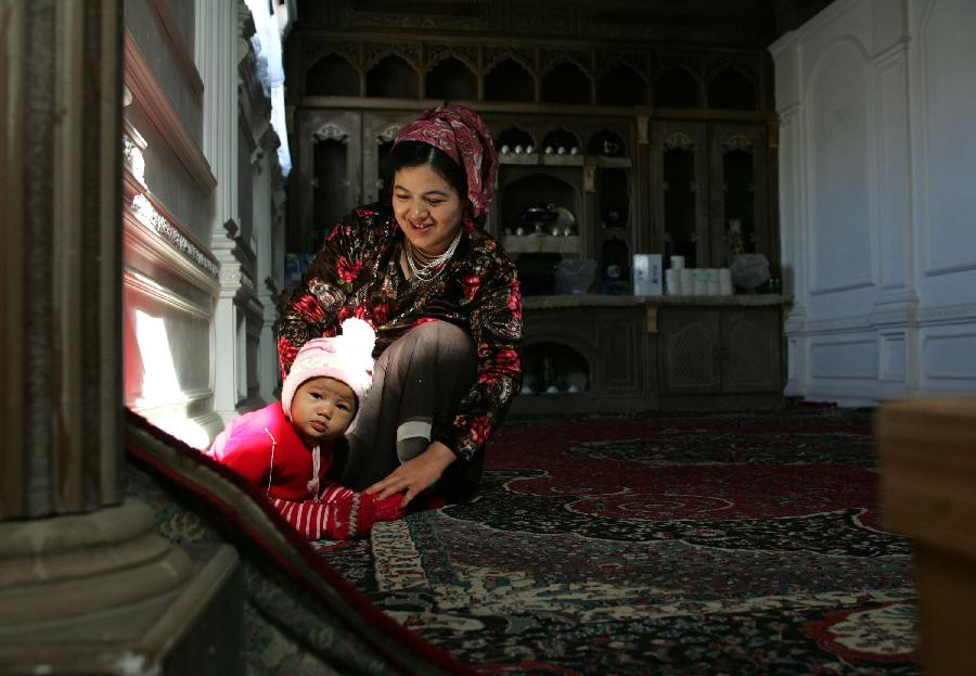 Mirnisa Abudulkader plays with her daughter at her house in the old city zone of Kashgar, northwest China's Xinjiang Uygur Autonomous Region, Oct. 21, 2011. 