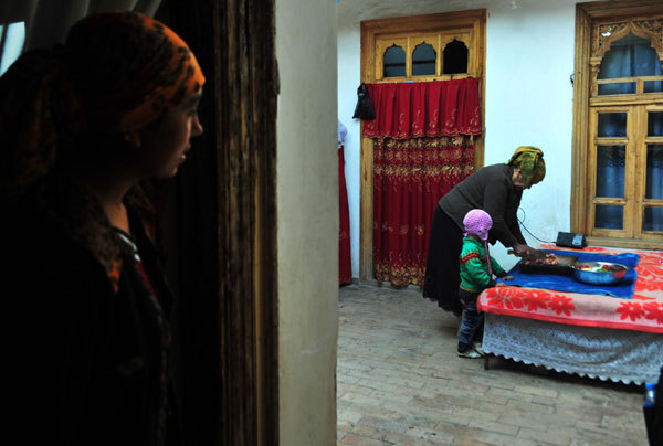 Bulpatman Mamat (back) makes preparation for cooking at her house in the old city zone of Kashgar, northwest China's Xinjiang Uygur autonomous region, Oct 21, 2011.[Photo/Xinhua]