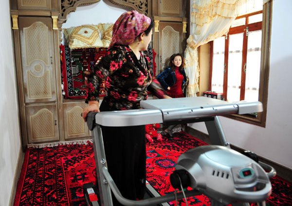 Mirnisa Abudulkader (L) standing on fitness equipment talks with community staff at her house in the old city zone of Kashgar, northwest China's Xinjiang Uygur autonomous region, Oct 21, 2011.[Photo/Xinhua]