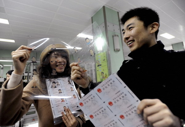 Residents in Shenyang, capital of Northeast China's Liaoning province, look at templates of the second generation ID card during their visit to the provincial public security department on March 23. [Photo by Zhang Wenkui/Xinhua] 