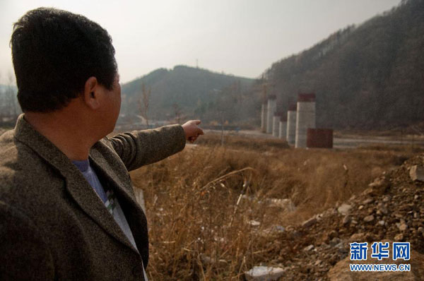 A worker points to the No 2 Bridge piers that were allegedly made with rubble, Oct 22, 2011. [Photo/Xinhua]