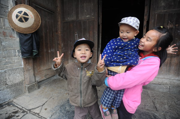 Holding her 2-year-old cousin, Long Zhanghuan (right) smiles with her little brother at home in Haoyou village, Hunan province, on Oct 24. [Photo/provided to China Daily]