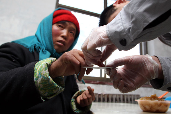 In this file photo taken on February 11, 2011, a medial worker takes blood samples of a street urchin for DNA test in a salvage center in Shijiazhuang, Hebei Province. The provincial police have rescued 206 foreign women who were illegally purchased by desperate bachelors over the last two years. 
