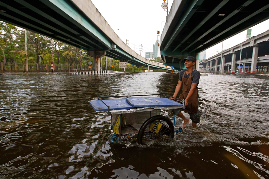 A resident travels on a boat as a bus drives on a flooded street in Bangkok Nov 5, 2011. Thailand's worst floods have left 506 people dead and 2 missing, Thai Department of Disaster Prevention and Mitigation reported on Sunday. 