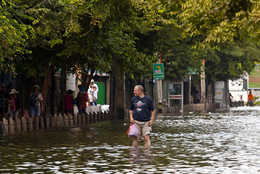 Residents travel on a boat as a bus drives on a flooded street in Bangkok Nov 5, 2011. Thailand's worst floods have left 506 people dead and 2 missing, Thai Department of Disaster Prevention and Mitigation reported on Sunday.