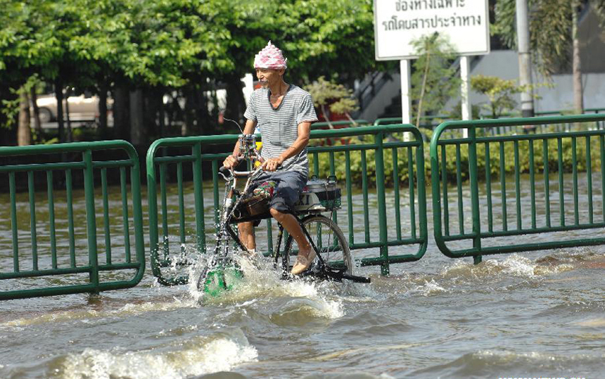 A bicyclist rides through floodwaters at an inundated street in Thai capital Bangkok Nov. 6, 2011. Thailand's worst floods have left 506 people dead and 2 missing, Thai Department of Disaster Prevention and Mitigation reported on Sunday. 